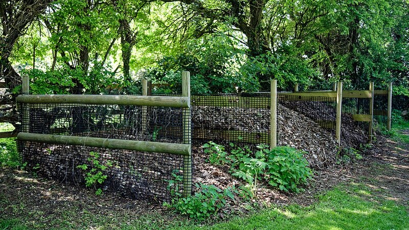 Timber compost bays heaped with leaves and green waste cleared during a garden clean-up